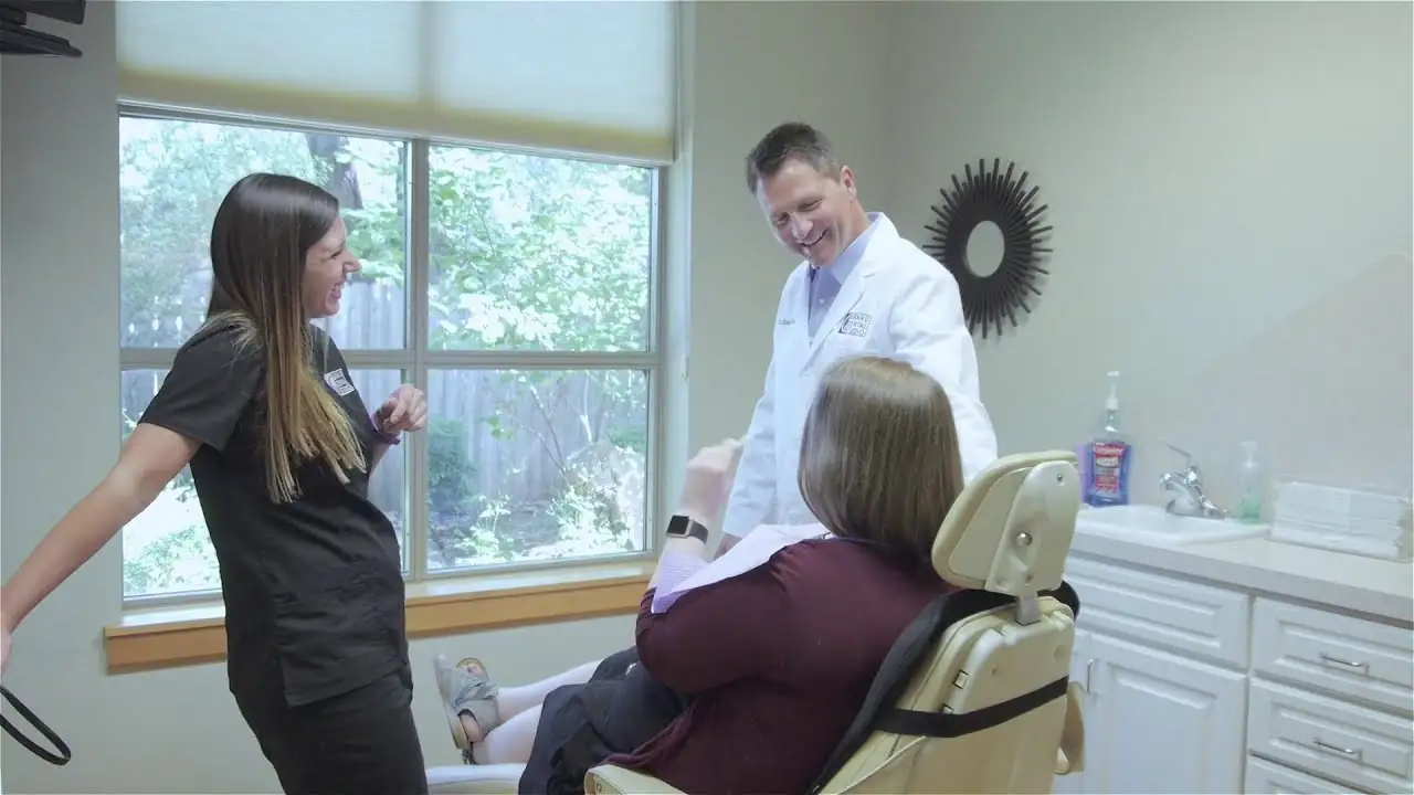 Dr. Michael Kirk talking with a dental assistant and a patient in a treatment room at Grand Dental Studio.