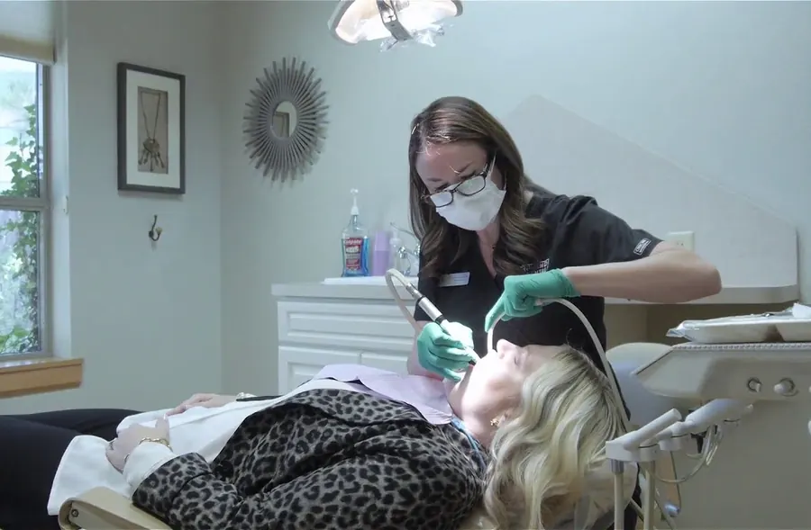 A Grand Dental Studio hygienist cleaning a patient's teeth in a treatment room.